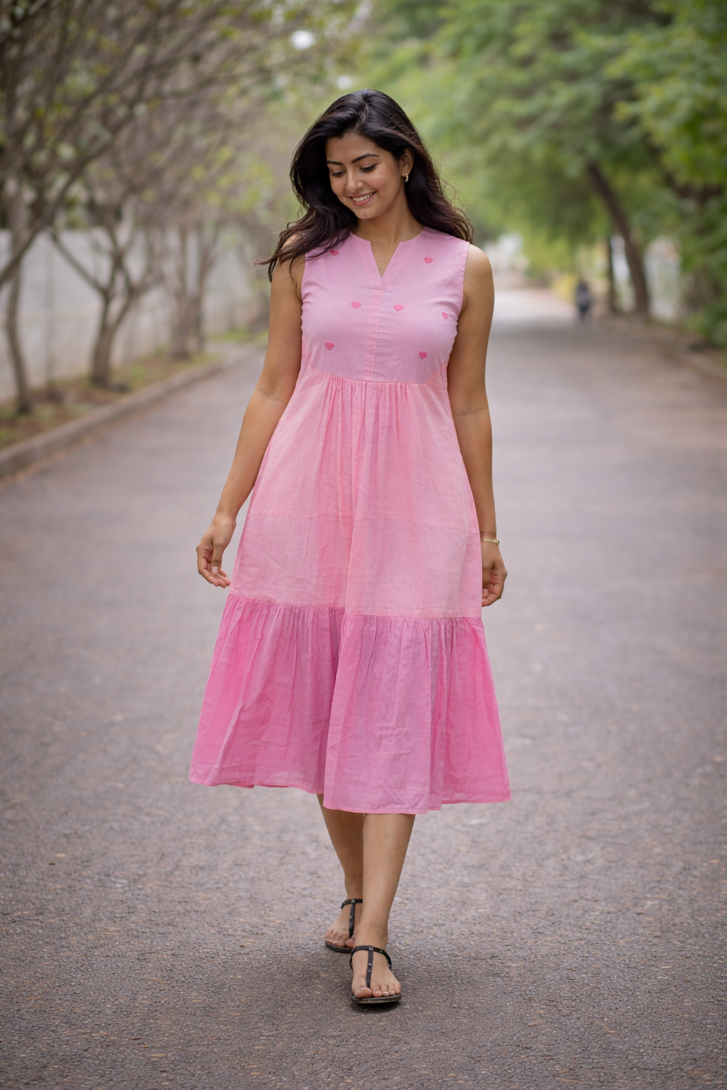 Woman wearing a pink dress walking on a path with trees in the background